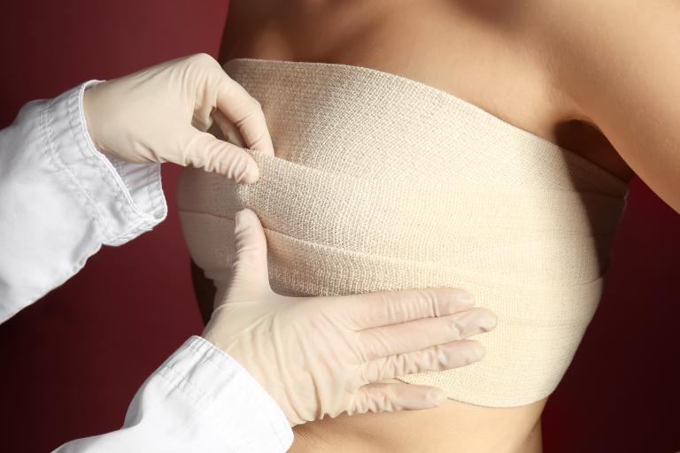 Doctor,applying,bandage,on,female,chest,after,cosmetic,surgery,operation